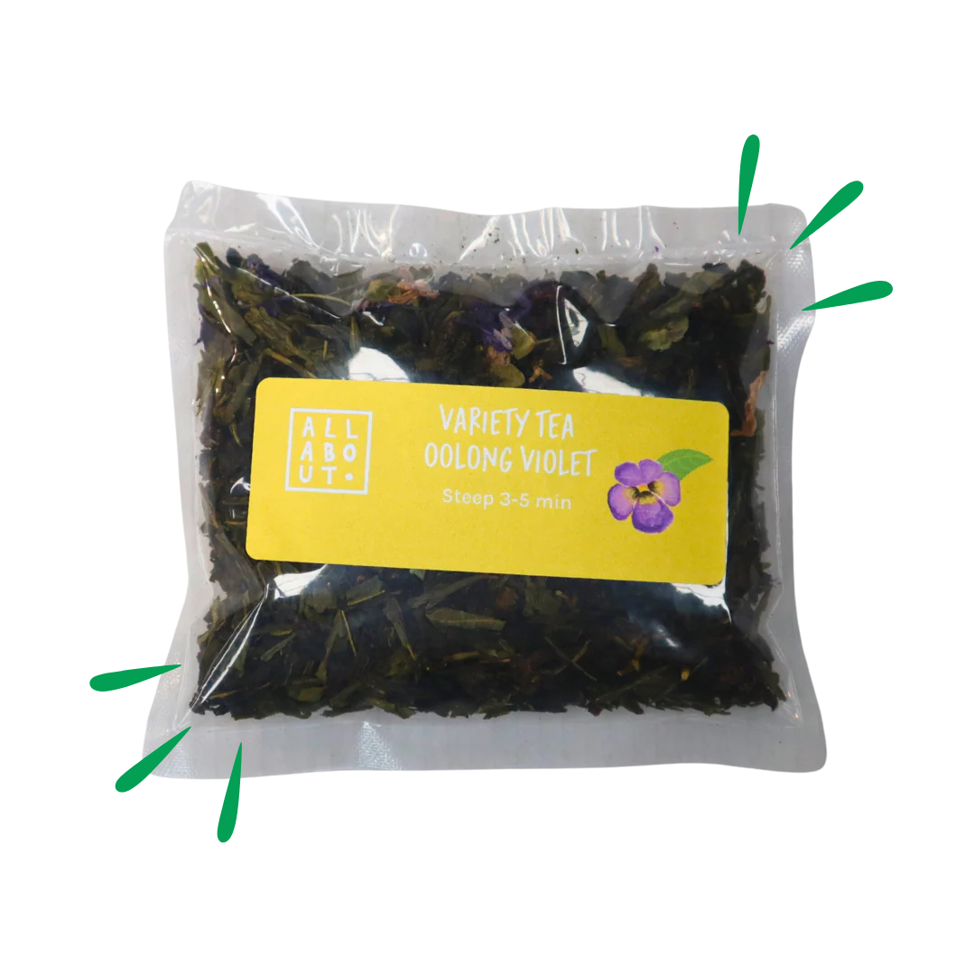 All About Kombucha variety tea pouch labeled Oolong Violet in a clear steeping pack with yellow label and violet flower illustration, containing floral loose tea blend.