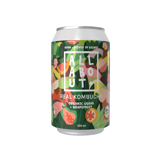 A 330 ml aluminum can of All About Real Kombucha Organic Guava + Grapefruit, featuring a colorful tropical fruit illustration on a dark green background.